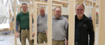 Gruppenfoto: Mitarbeiter von Grathwol Fensterbau hintereinander aufgereiht zwischen Holz-Fensterrahmen.