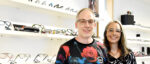 Augenoptiker- und Hörakustikermeister Daniel Benner steht mit seiner Frau vor einem Regal mit Brillen.